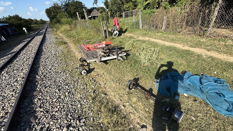 A dismantled bamboo train lying on the ground next to the railway tracks