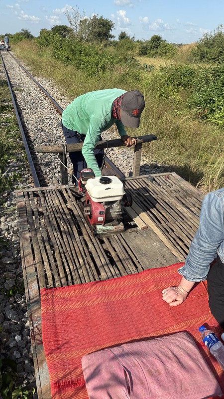 A bamboo train, a platform made of bamboo with a engine atop of it, Susan is sat on the platform
