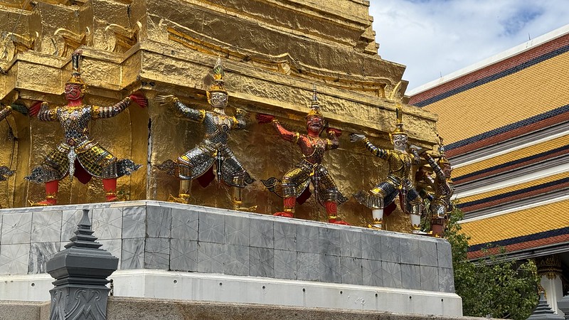 A row of Thai Dragon men holding up a golden part of the temple in the grounds of the Grand Palace