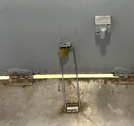 A small brass padlock keeping a keeping a train door closed