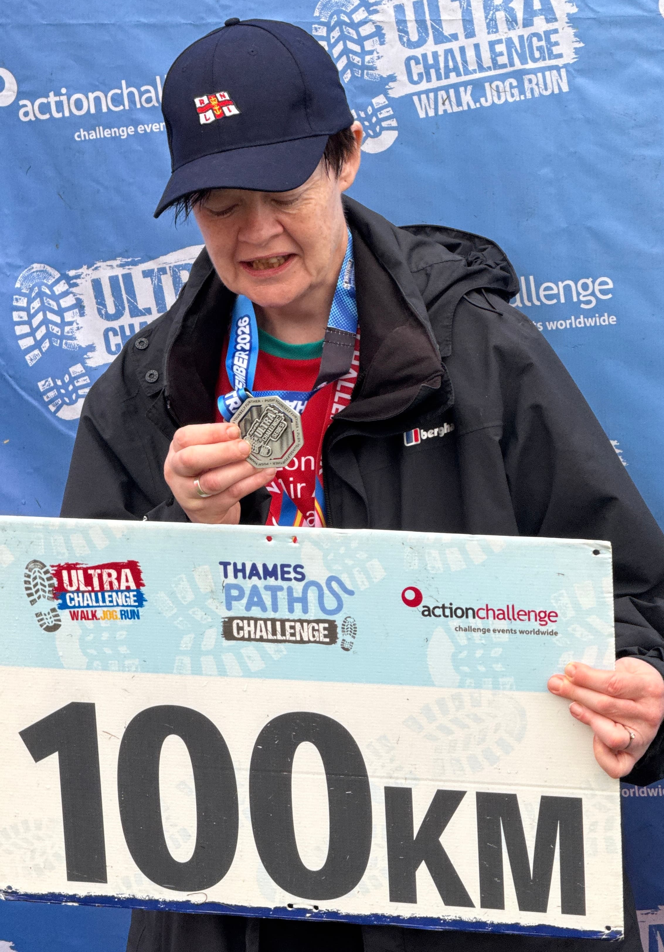 Susan with her well deserved medal and holding a sign that reads 100km